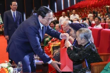 Le Premier ministre Pham Minh Chinh remet des cadeaux à des personnes ayant rendu des services méritoires à la révolution. Photo: VNA.
