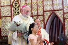 Une jeune fille présente des fleurs à l’archevêque Paul Richard Gallagher, secrétaire du Vatican pour les Relations avec les États et les organisations internationales. Photo : VNA.