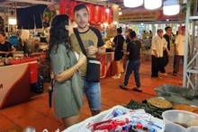 Maria et son petit ami cherchent des plats vietnamiens lors du festival le soir du 23 octobre. Photo : Bich Phuong. 