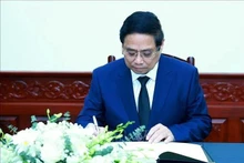 Le Premier ministre Pham Minh Chinh écrit dans le registre de condoléances. Photo : VNA. 