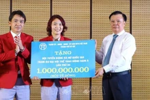 Le secrétaire du Comité du Parti de la ville de Hanoï, Dinh Tien Dung, remet un milliard de dongs de la ville à l'équipe de football féminin du Vietnam qui a remporté la médaille d’or aux SEA Games 32 au Cambodge. Photo : VNA