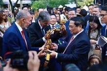 Le Premier ministre Pham Minh Chinh offre des marionnettes sur l'eau à des délégués. Photo : VNA