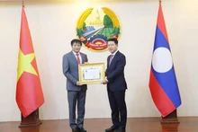Le vice-Premier ministre et ministre des Affaires étrangères du Laos, Saleumxay Kommasith (droite), remet la noble distinction à l'ambassadeur Nguyen Ba Hung. Photo : VNA.
