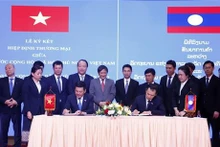  Le ministre de l'Industrie et du Commerce, Nguyen Hong Dien (gauche), et son homologue lao, Malaithong Kommasith, signent un nouvel accord commercial Vietnam-Laos. Photo: VNA