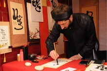 Jean Sébastien Grill, un étranger « Ông dô » (maître calligraphe) porte un « áo the » (tunique traditionnelle masculine vietnamienne) et un « khăn xếp » (turban), ses yeux se sont concentrés sur chaque coup de plume. Photo : thoidai.com.vn