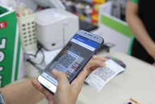 Une cliente paie via QR Code. Les Vietnamiens ont moins d’argent liquide dans leur portefeuille. Photo: VNA