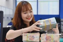 Un caissier de banque compte l’argent dans un bureau de transactions à Hanoï. Photo : cafef.vn