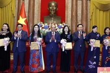 Le Président Nguyen Xuan Phuc (4e, gauche), le Premier ministre Pham Minh Chinh (2e gauche), le Président de l'Assemblée nationale Vuong Dinh Hue (3e, droite) offrent des cadeaux aux déléguées. Photo: VNA