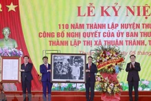 Le Président de l'Assemblée nationale, Vuong Dinh Huê, remet la photo de l'Oncle Hô et la Résolution du Comité permanent de l'AN aux autorités de Thuân Thành sur la création de la cité municipale de Thuân Thành. Photo : VNA.