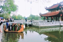 Les membres du Club du chant alterné "Quan họ" du temple Dô se produisent à la maison communale sur un lac du temple Dô. Photo : NDEL.