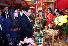 Le Premier ministre Pham Minh Chinh et son épouse visitent un stand du Têt de la communauté vietnamienne lors de l'événement. Photo : VNA.