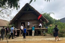 Les touristes visitent la maison Ede au village culturel et touristique ethnique au Vietnam. Photo : NDEL.