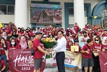 Le dirigeant du Service du Tourisme de Ha Long offre des fleurs à un groupe de tourisme venus de Malaisie. Photo : baoquangninh.vn