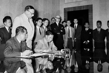 Le vice-ministre de la Défense Ta Quang Buu (assis, à droite), de la délégation de la République démocratique du Vietnam, et le général français Henri Delteil, commandant en chef par intérim des forces de l’Union française en Indochine, signent l’accord de cessation des hostilités au Vietnam. Photo d’archives : VNA