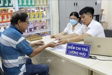 Une personne âgée d'Hô Chi Minh-Ville reçoit une pension dans un bureau de poste. Photo : VNA.