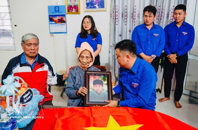 Des jeunes de Da Nang remettent des portraits de martyrs restaurés à leurs proches. Photo : VNA