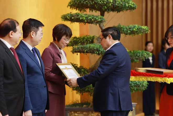 Le Premier ministre Pham Minh Chinh remet le certificat de mérite du Comité du Parti du gouvernement à Vu Viet Trang, directrice générale de l'Agence vietnamienne d'Information. Photo : VNA