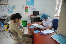 Le personnel médical examine et vérifie l'état de santé de l'enfant avant la vaccination. Photo : VNA.