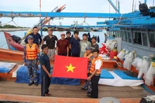 Des officiers de l'île de Song Tu Tay offrent des cadeaux et de la nourriture aux pêcheurs venus se réfugier sur l'île pour échapper à la tempête. Photo : NDEL.