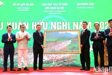 Des représentants de la commune de Huong Son offrent à la délégation une peinture représentant le ruisseau Yen, située dans le complexe historique de Huong Son. Photo : NDEL.