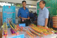 Thạch Rô Si Dol (en chemise bleue) présente sa maquette de ghe Ngo lors de l’événement "Concours de projets de start-up des jeunes ruraux 2023". Photo : VOV.