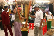 Des touristes découvrent la fabrication traditionnelle du cốm dẹp chez les Khmers de Soc Trang, aujourd’hui Can Tho. Photo : laodong.vn