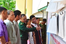 Des cadres du poste de garde-frontière de Ia Nan, avec des patriarches, guident les habitants à consulter les informations sur les candidats aux élections de l’Assemblée nationale et des conseils populaires. Photo : Baotintuc.
