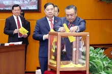 Les délégués procèdent au vote lors du premier plénum du Comité central du Parti du XIVe mandat, dans la matinée du 23 janvier. Photo : VNA.