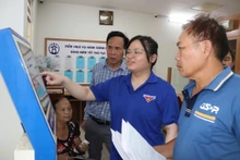 Les membres de l'Union des jeunes de la commune de Bat Trang aident les habitants au guichet de services administratifs publics de la commune. Photo : Phuong Loc. 