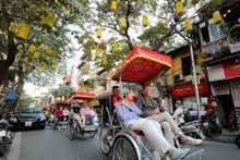 Les touristes étrangers visitent les rues en cyclo-pousse, admirant la beauté antique d'Hanoï. Photo : VNA.