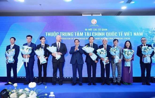 Le Premier ministre Pham Minh Chinh offre des fleurs aux représentants des agences relevant du Centre financier international du Vietnam. (Photo : VNA)