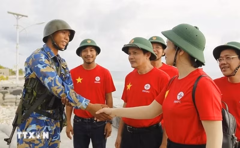 Des représentants du groupe EVN et un soldat sur l'île de Song Tu Tay. Photo : VNA