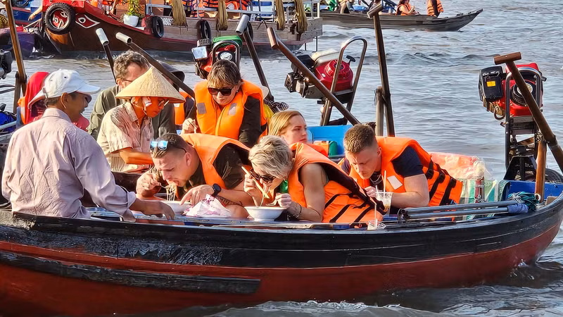 De nombreux touristes étrangers aiment prendre leur petit-déjeuner, boire du café ou déguster des fruits au milieu du marché flottant de Cai Rang. Photo : Toquoc.vn De nombreux touristes étrangers aiment prendre leur petit-déjeuner, boire du café ou déguster des fruits au milieu du marché flottant de Cai Rang. Photo : Toquoc.vn