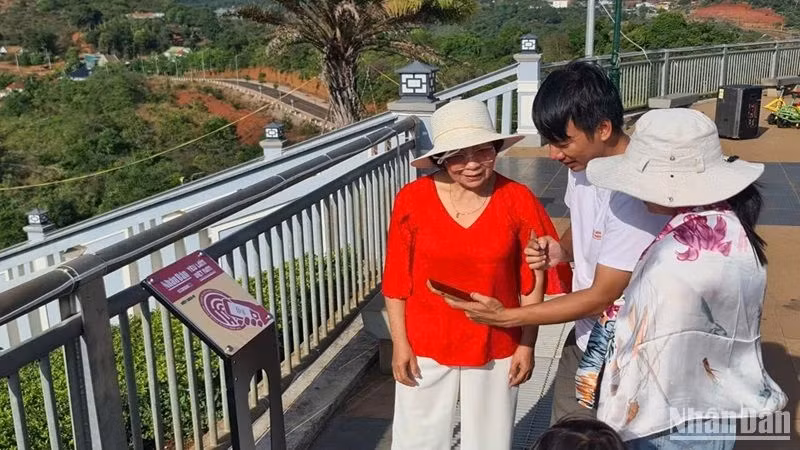 Guide des visiteurs pour effectuer les opérations de check-in sur les panneaux équipés de puces NFC installés dans la ville de Gia Nghia, province de Dak Nông. Photo: nhandan.vn