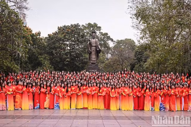 500 étudiantes de l’Académie des femmes du Vietnam, habillées d’ao dài rouges ornés d’une étoile jaune, posent pour une photo souvenir devant la statue du roi Ly Thai Tô. Photo : nhandan.vn