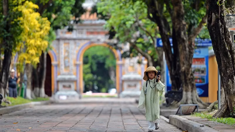 Une petite fille vêtue de l’ancien costume a suivi sa mère dans l'enceinte du Dai Nôi de Huê, en écoutant attentivement la présentation automatique via le dispositif du service touristique. Photo : nhandan.vn