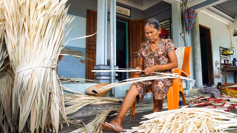 Une artisan est en train de tresser un éventail en feuilles de « buông ». Photo : daidoanket.vn