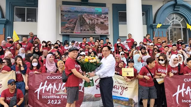 Le dirigeant du Service du Tourisme de Ha Long offre des fleurs à un groupe de tourisme venus de Malaisie. Photo : baoquangninh.vn