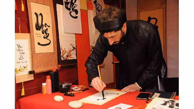 Jean Sébastien Grill, un étranger « Ông dô » (maître calligraphe) porte un « áo the » (tunique traditionnelle masculine vietnamienne) et un « khăn xếp » (turban), ses yeux se sont concentrés sur chaque coup de plume. Photo : thoidai.com.vn