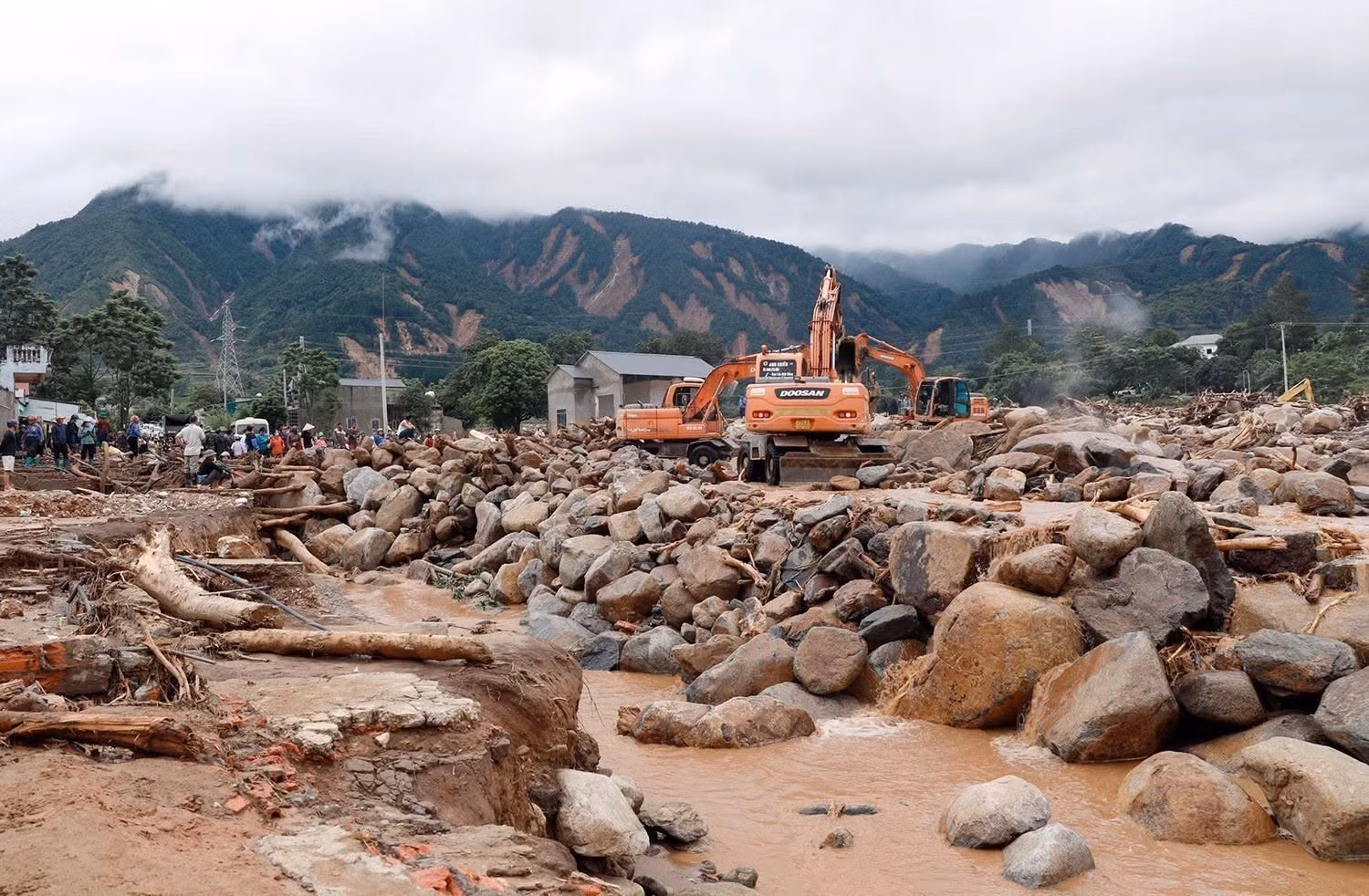Des engins mécaniques sont mobilisés pour déblayer les arbres, la terre et les rochers, contribuant à rétablir temporairement la circulation pour les habitants. Photo : VNA