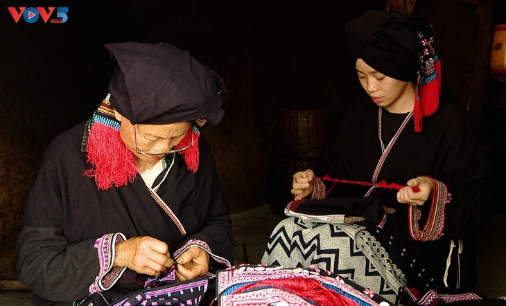Dang Thi Vinh brode un vêtement traditionnel aux côtés de sa petite-fille. Photo : VOV5