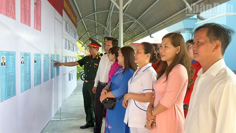 Des cadres et des habitants consultent les listes des candidats.