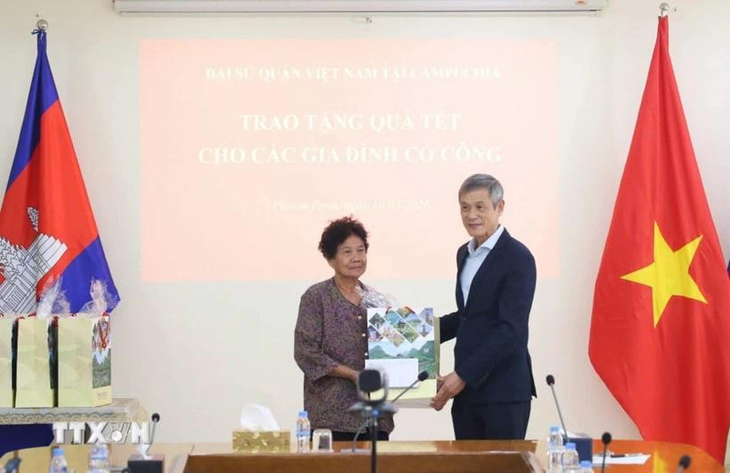 L'ambassadeur Nguyen Minh Vu remet des cadeaux du Têt à Ha Thi E, qui a contribué à la résistance contre l'armée américaine et a reçu un certificat de mérite du Premier ministre vietnamien en 2009. Photo : VNA.