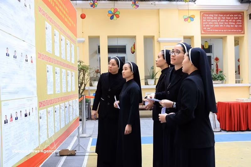 Des religieuses de la Congrégation des Amantes de la Sainte-Croix, au 31 rue Nhà Chung, consultent la liste des candidats au bureau de vote n°1, dans le quartier de Hoàn Kiem. Photo : VNA