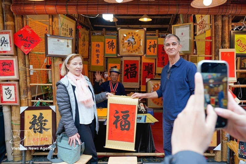 Des visiteurs internationaux participent à l’activité traditionnelle de demande de calligraphie en début d’année. Photo : VNA.