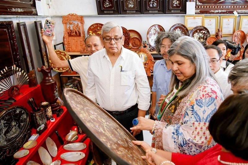 Des visiteurs internationaux découvrent avec enthousiasme et participent à des expériences au village artisanal de marqueterie de nacre de Chuyen My. Photo : Minh Loc