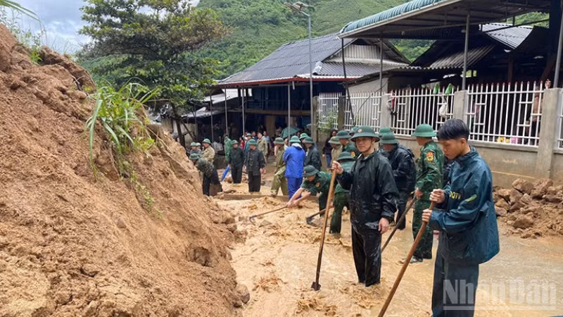 Les soldats de la Garde-frontière de la région montagneuse de Thanh Hoa dégagent la terre et les rochers tombés de la pente sur la route locale. (Photo : NDEL)
