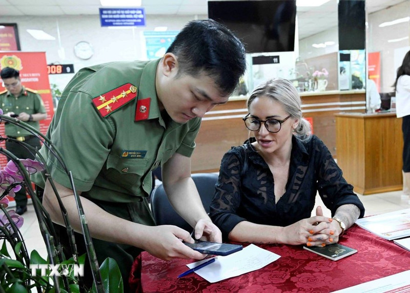 Les cadres et soldats du Département de gestion de l’immigration du ministère de la Sécurité publique guident les étrangers dans les démarches de création d’un compte d’identification électronique. Photo : VNA.