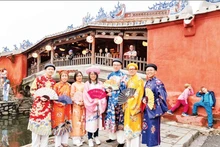 Des touristes portant des costumes traditionnels vietnamiens explorent la vieille ville de Hoi An (Da Nang). Photo : NDEL 