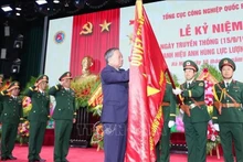 Le secrétaire général du Parti To Lam épingle l’insigne de Héros des Forces armées populaires sur le drapeau traditionnel du Département général de l’industrie de la défense. Photo : VNA.
